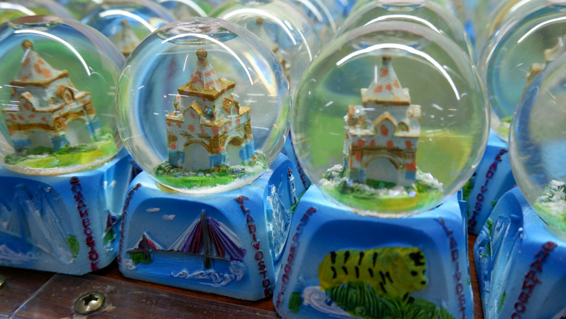 Multiple crystal balls are displayed on shelves, each containing unique landscapes.