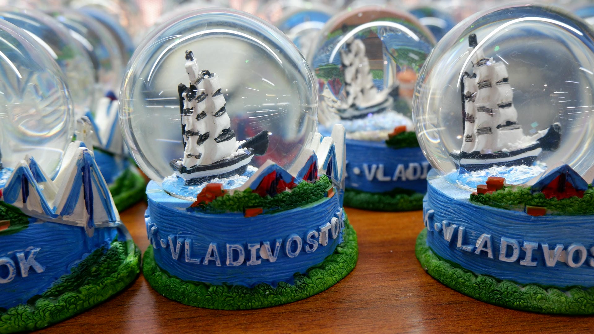 A crystal ball contains a model sailboat, with “VLADIVOSTOK” on the base, surrounded by blue decorations.