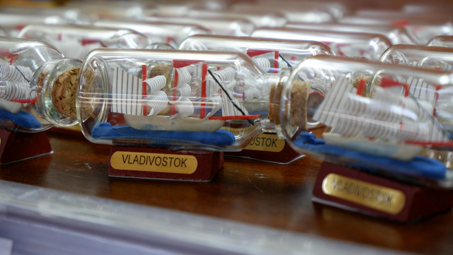 A row of miniature sailboats in bottles, labeled “VLADIVOSTOK.”