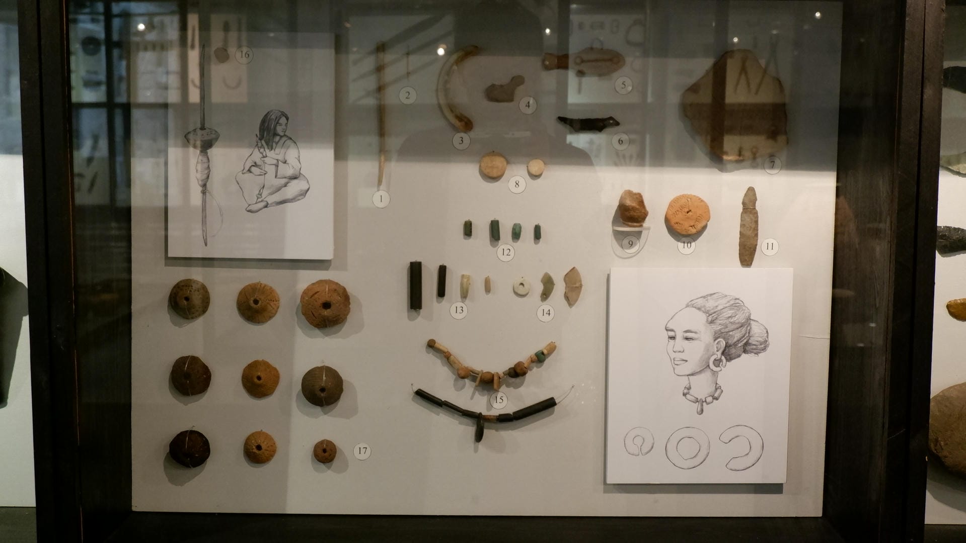 A display case contains various ancient ornaments and items, including necklaces, beads, and carvings.