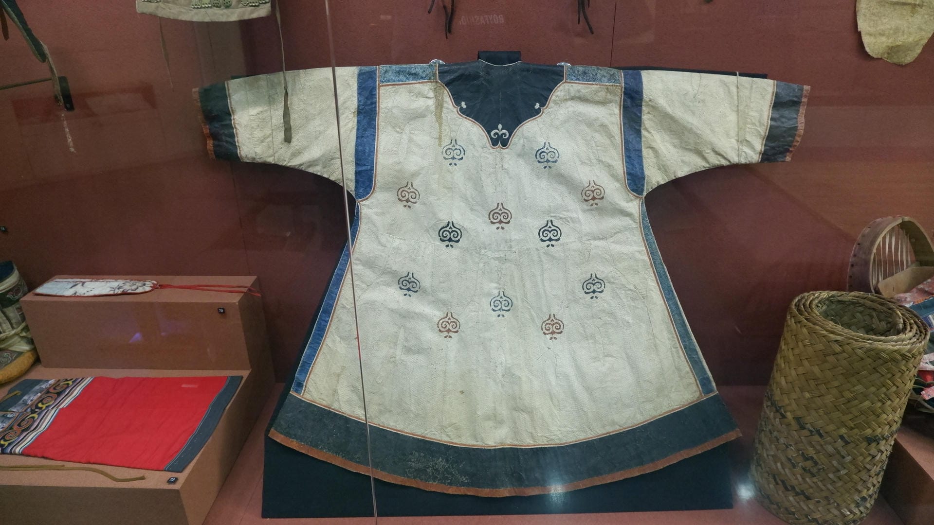 A white robe is laid flat on the display platform, decorated with blue patterns.
