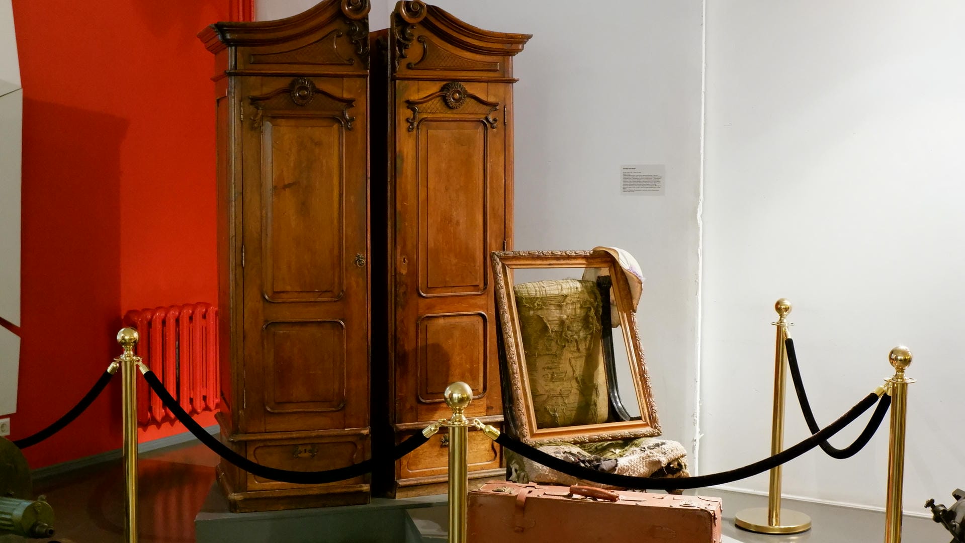 Two wooden wardrobes and a broken chair protected by a fence.