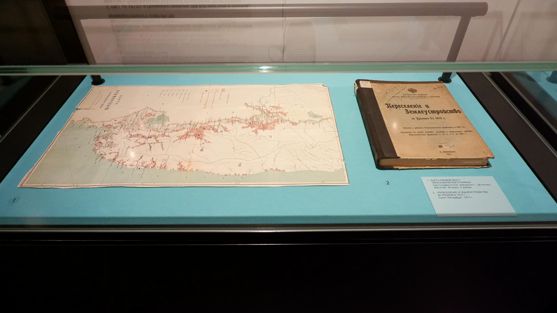 An old map and a book titled 《Migration and Land Use》 displayed on a blue cushion.