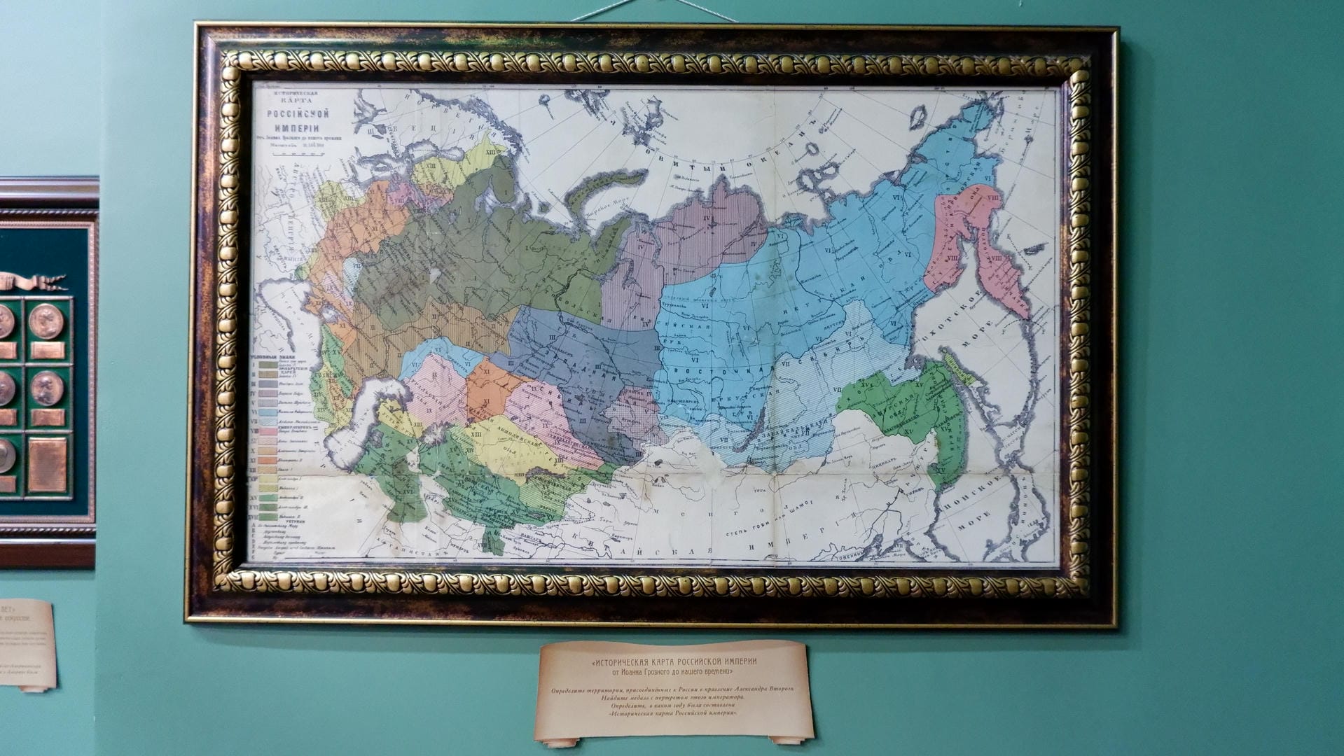 A beautifully framed historical map of the Russian Empire hangs on the wall, with an explanatory plaque beside it.