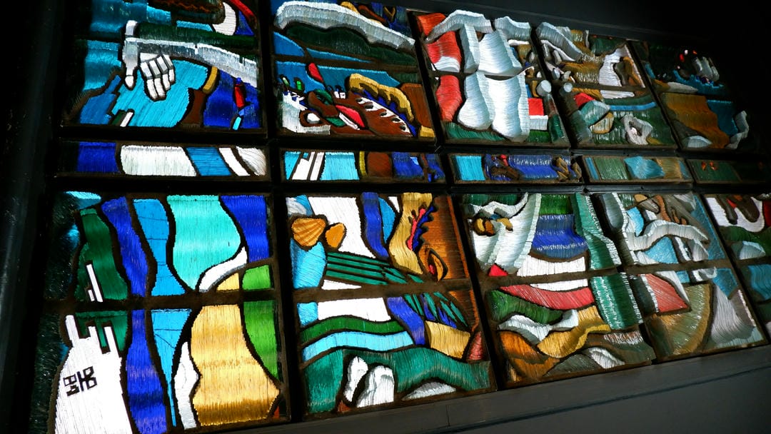 Stained glass windows depicting abstract patterns, including figures and animals.
