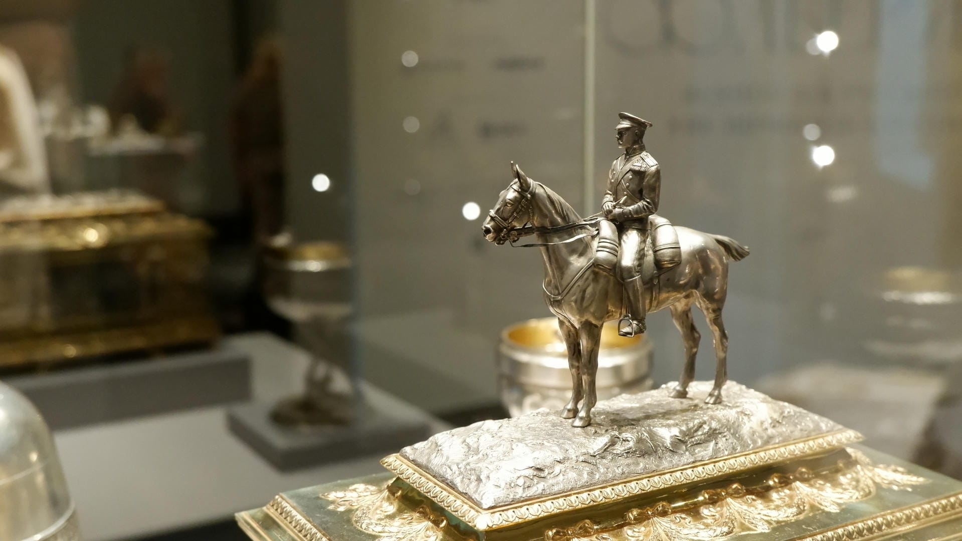 A silver equestrian statue placed on an elaborately decorated base.