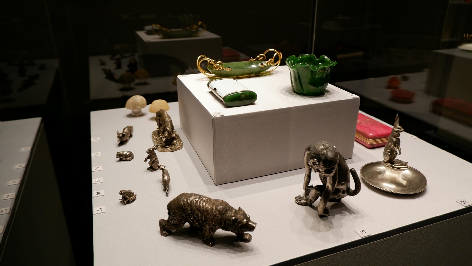 Small animal-shaped figurines, including monkeys, bears, and rabbits, along with some green decorations, displayed in a showcase.