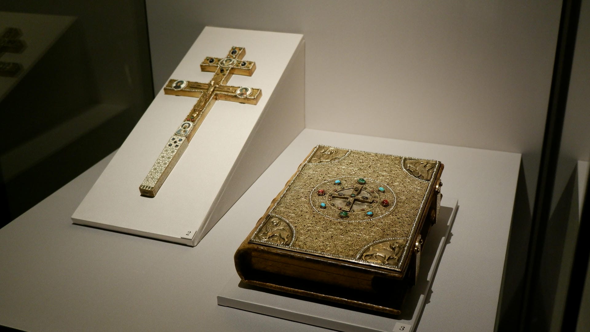 A golden cross and an ornate book with gem-encrusted cover.