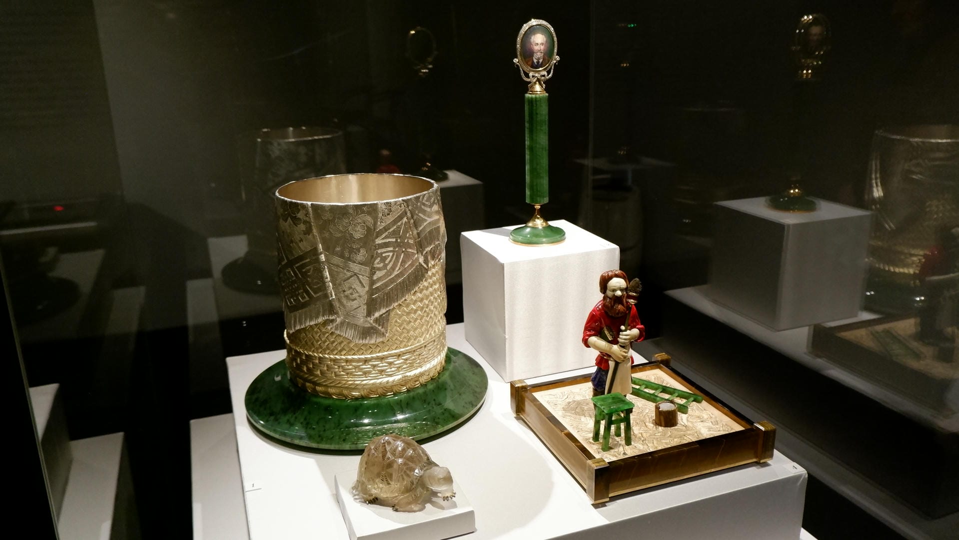 Metal containers with green bases, cylindrical green objects, and a small figurine displayed in a showcase.