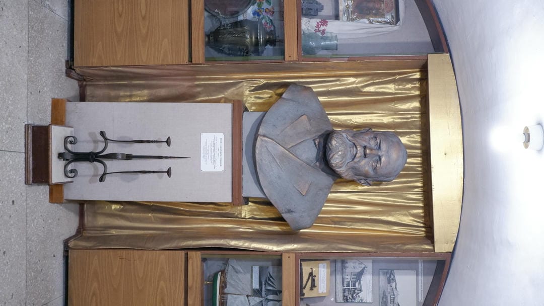 A bust of a man with a golden curtain in the background and a candlestick in the foreground.