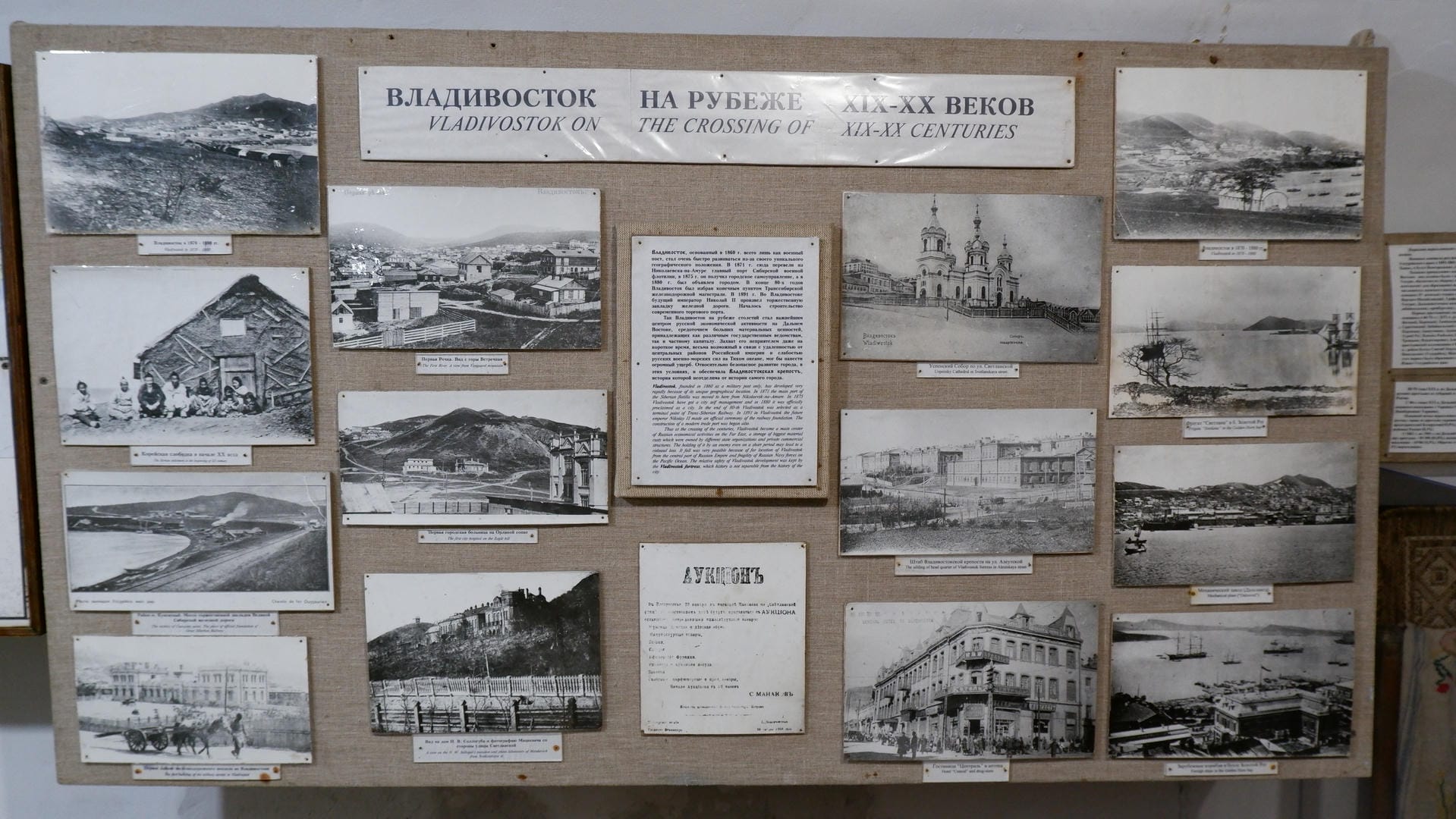 A display board with multiple black-and-white photos titled “Vladivostok on the Crossing of XIX-XX Centuries.”