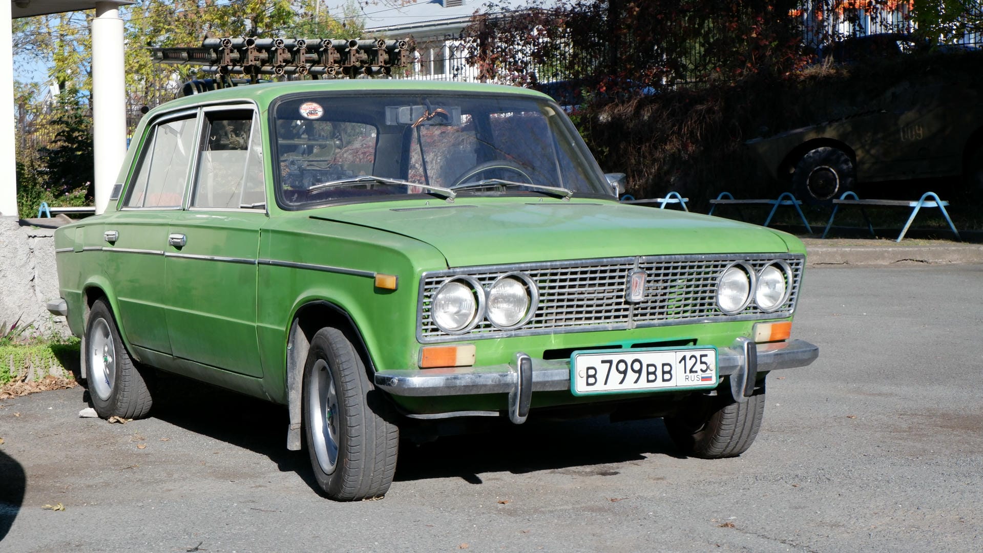 A green vintage car parked by the roadside, with license plate number B799BB 125.