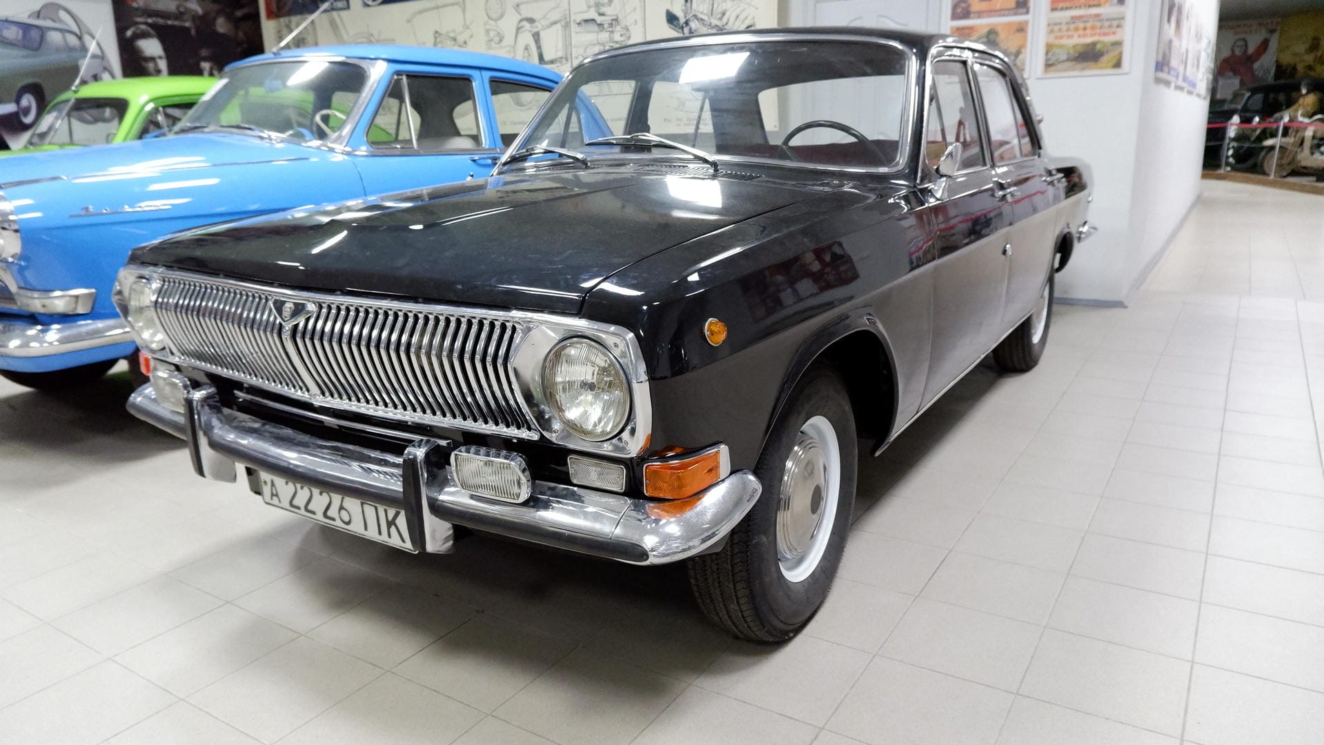A black vintage car parked inside an exhibition hall, with license plate А 2226 ПК.
