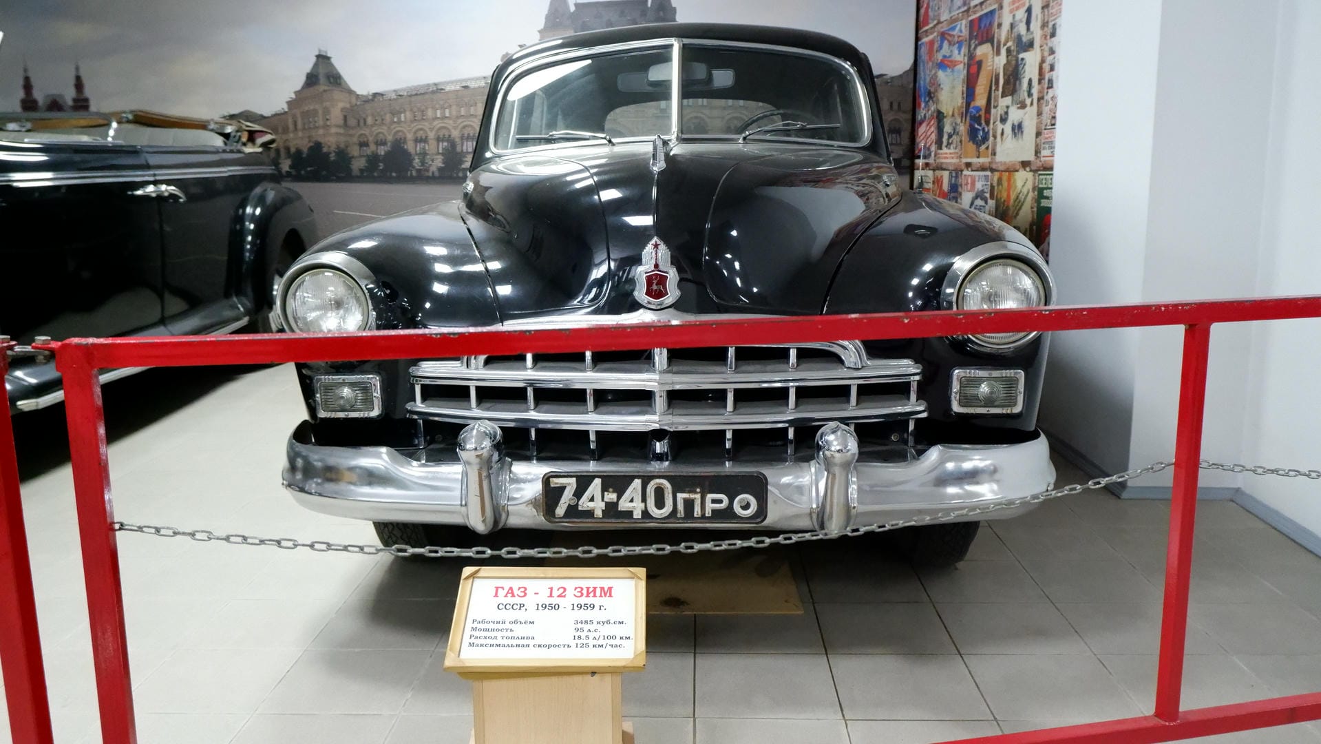 A black vintage car with license plate “74-40ПРО,” with a red railing in front.