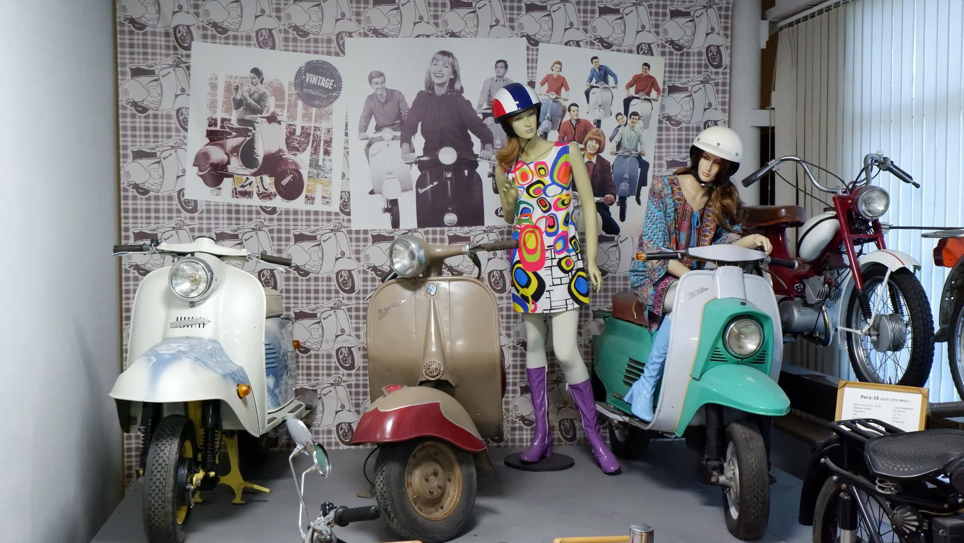 Several retro motorcycles and two mannequins dressed in retro clothing, with motorcycle patterns on the background wall.