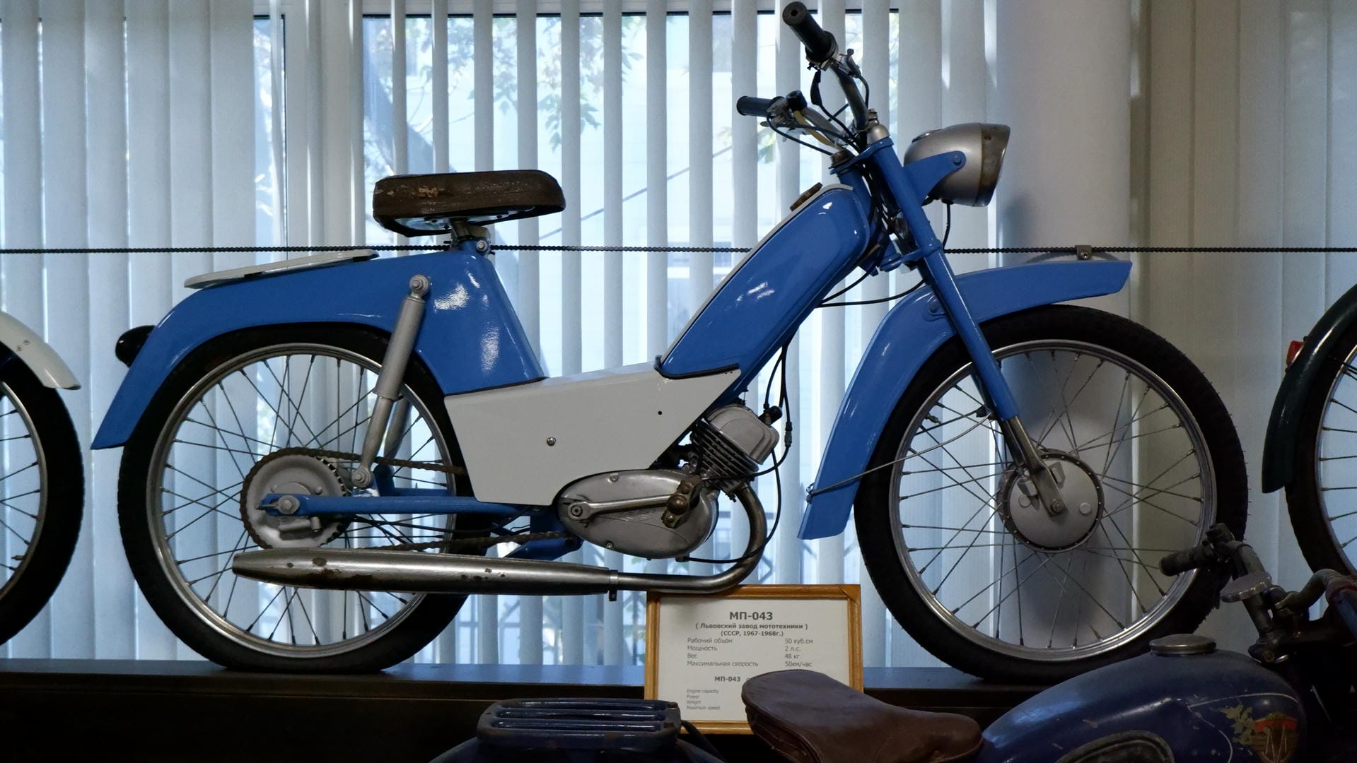 A blue motorcycle with silver frame and rims, and a black seat.