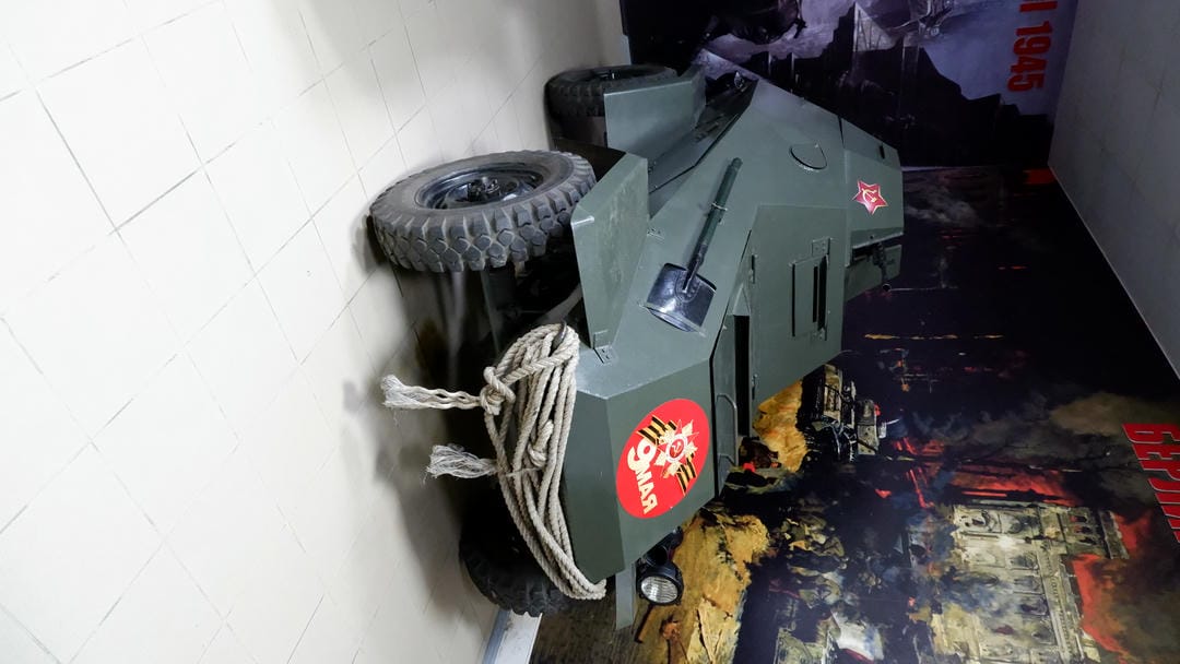 A green armored vehicle with red markings and ropes on the body.