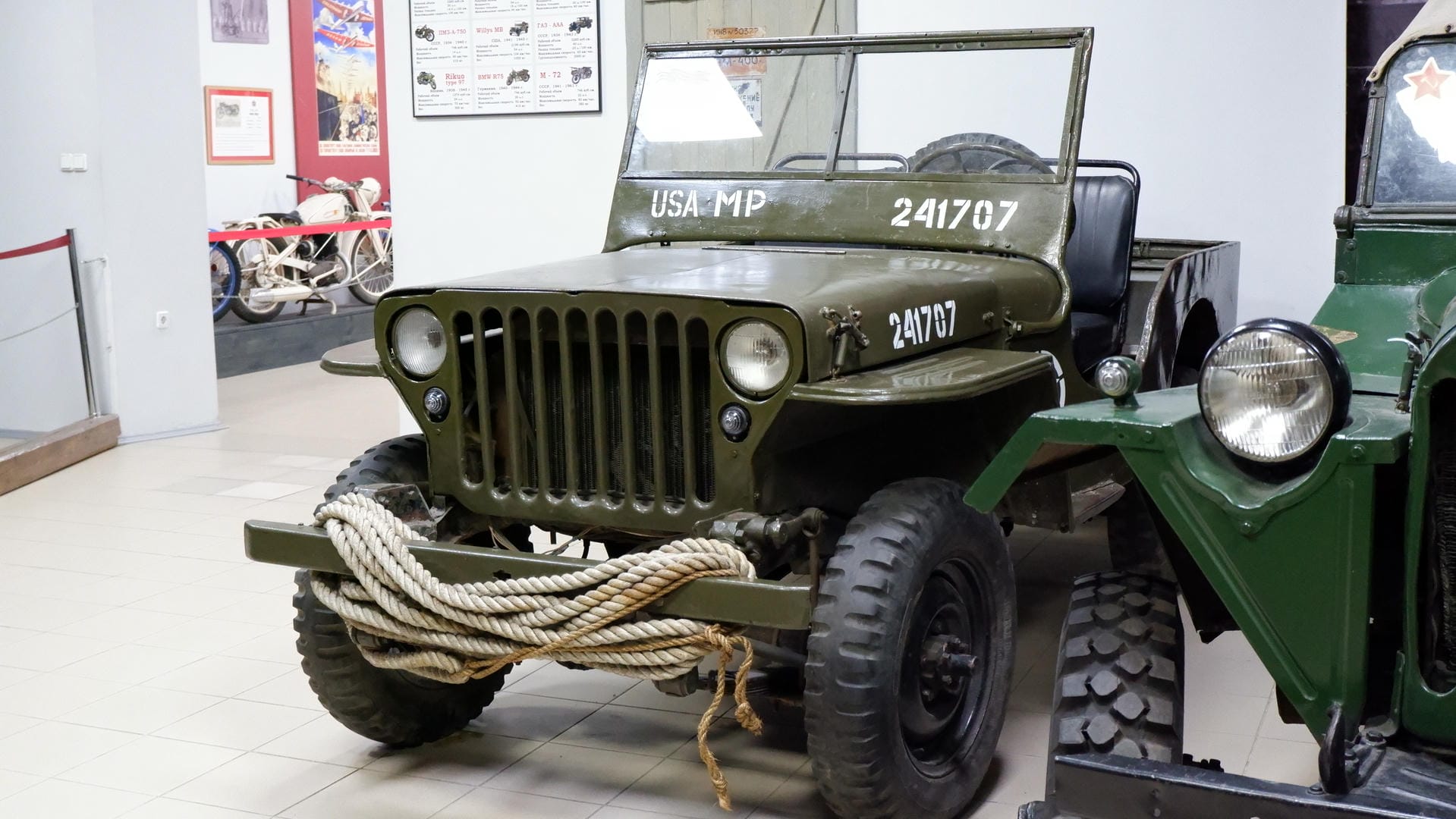 A green military vehicle with “USA MP” and number “241707” on the front, with thick ropes wrapped around the bumper.
