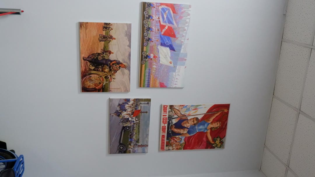 Four paintings on the wall depicting different scenes, including sports events and military activities.