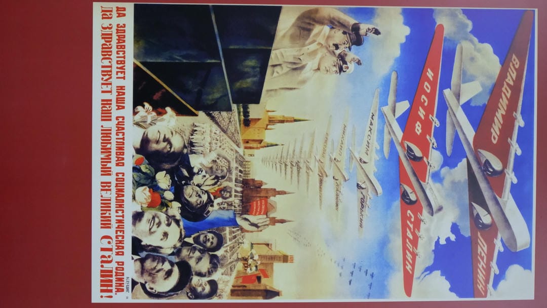 A poster showing multiple planes flying over Moscow’s Red Square, with cheering crowds below and a Russian slogan at the bottom.