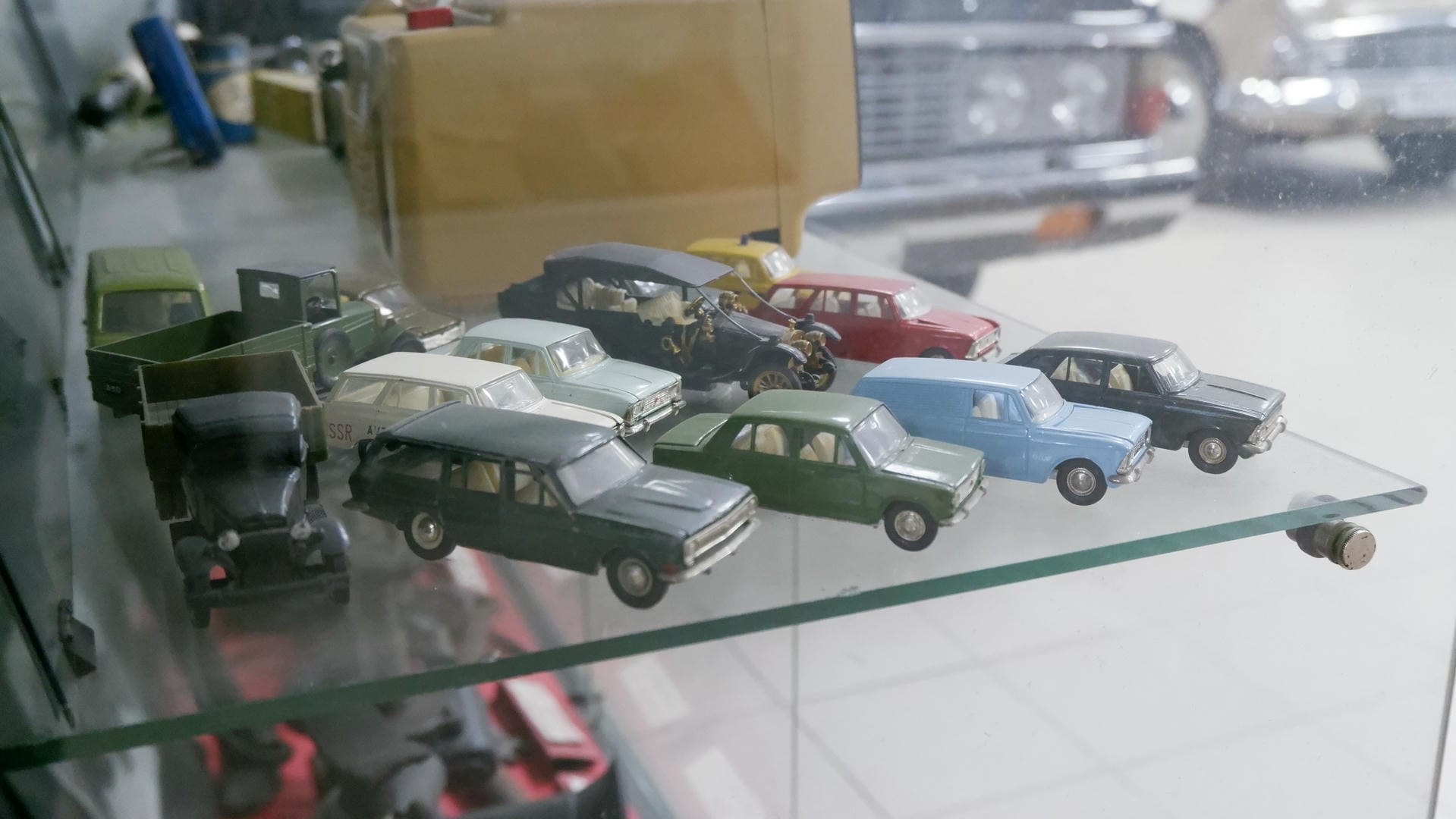 A glass display case exhibiting miniature car models of different colors and styles.