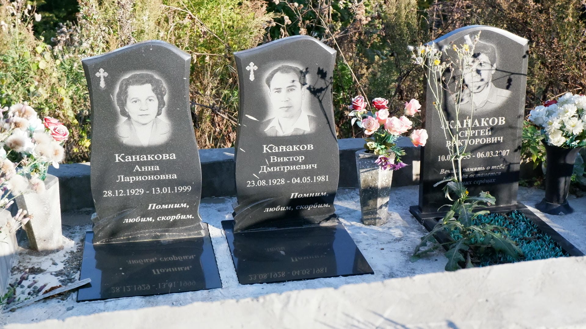 Three tombstones respectively engraved with photos and birth-death years of Anna Kanakova, Viktor Kanakov, and Sergey Kanakov.