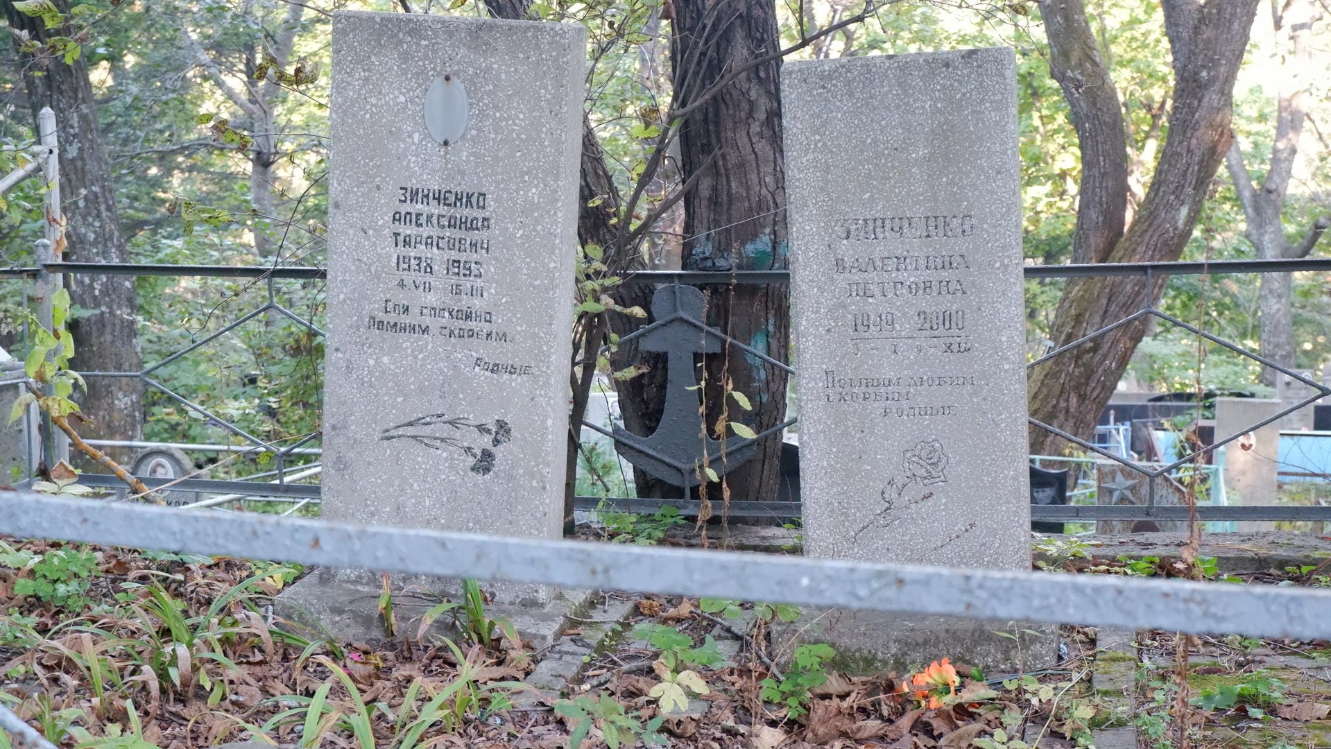 Two tombstones engraved with photos and birth-death years of Alexander Zinchenko and Valentina, with an anchor-shaped decoration in between.