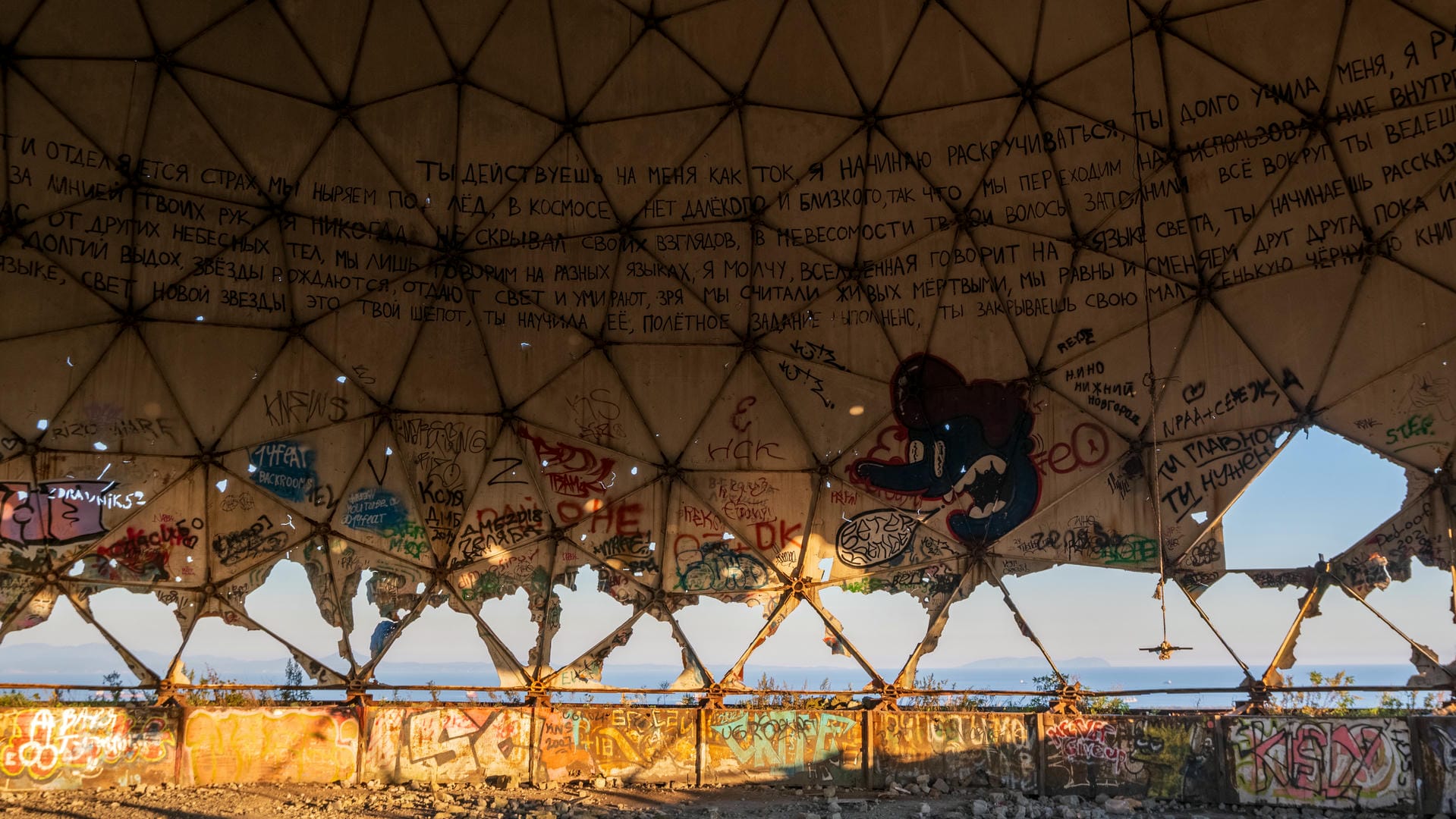 Inside the dome structure, the walls are covered in graffiti and text, with parts of the ceiling damaged.
