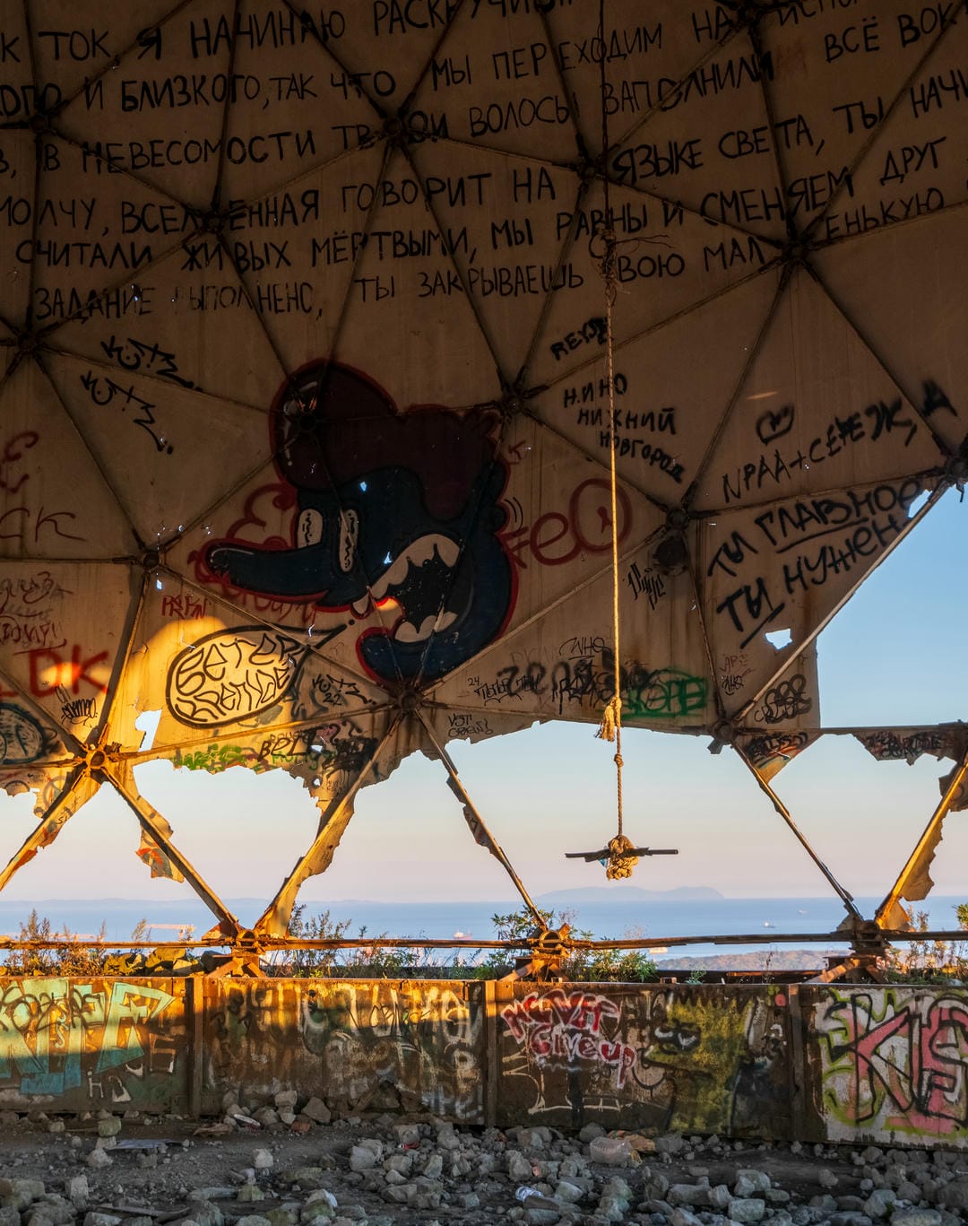 A close-up inside the dome structure, with a black cartoon figure at the center of the ceiling, surrounded by various graffiti.