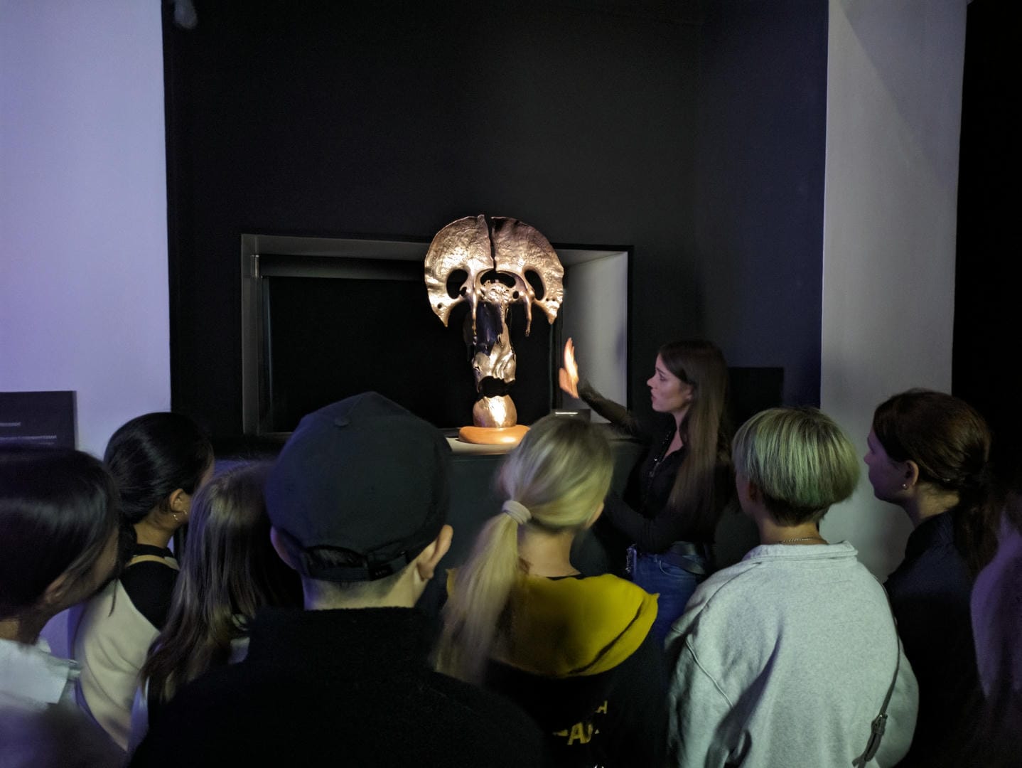 A group listens to the guide introducing a skull fossil exhibit.