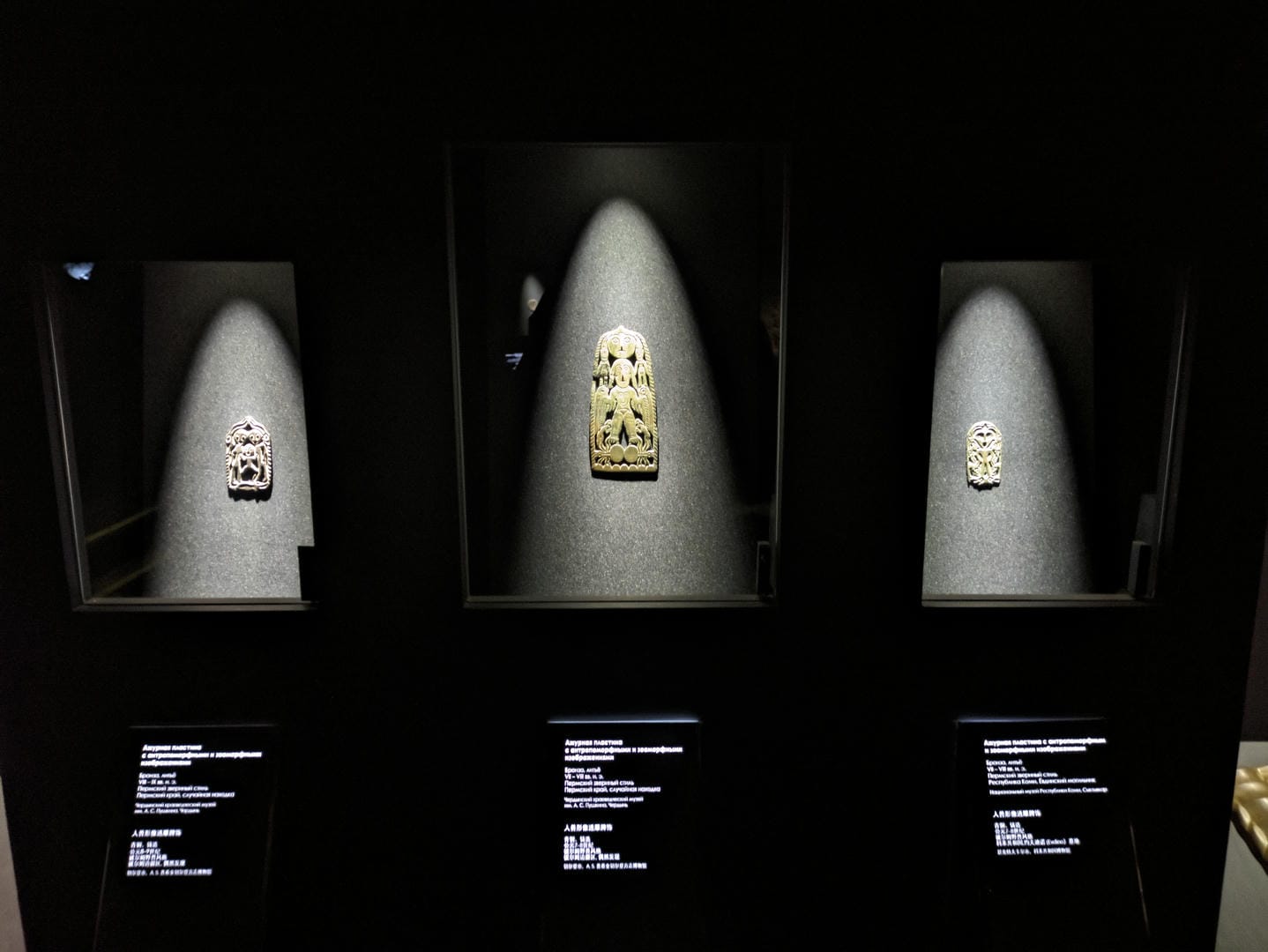 Three independent display cases each show different small carved artworks.