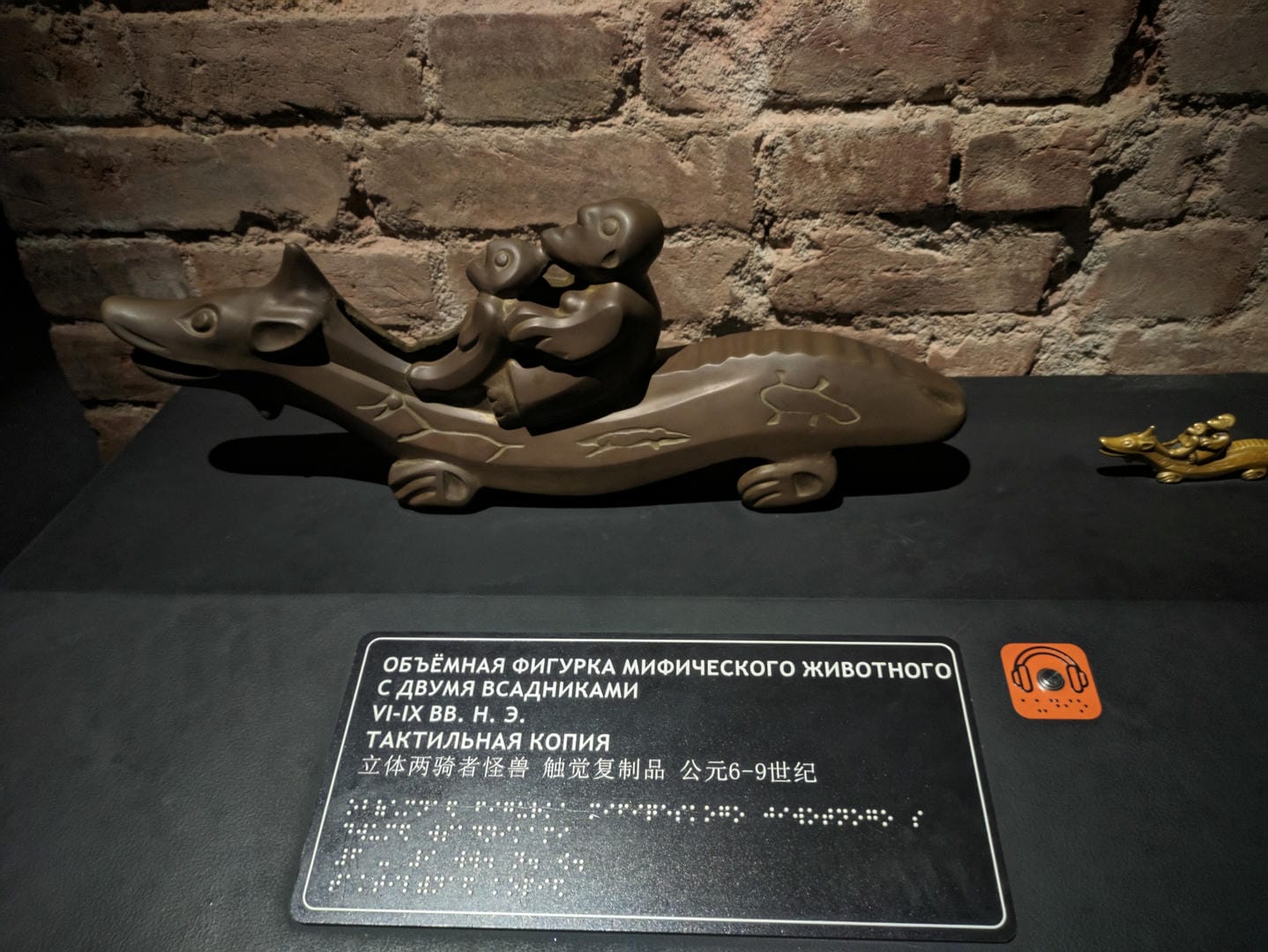A tactile replica of a two-headed monster rider, with explanatory text beside it.