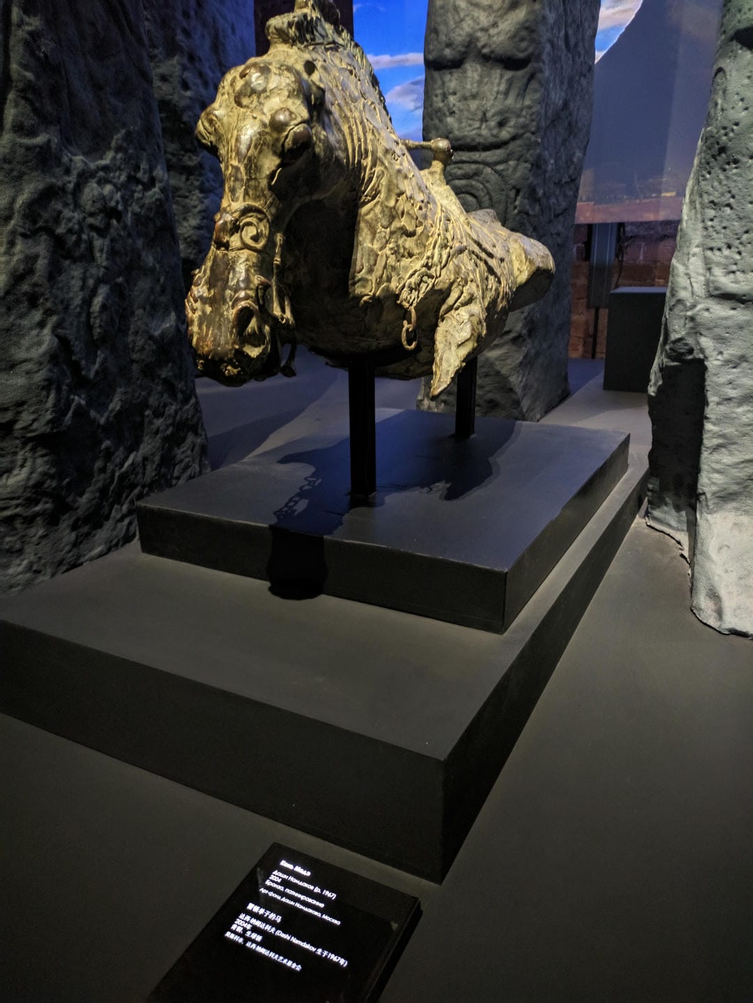 A golden horse head sculpture with a rock-like decoration in the background.