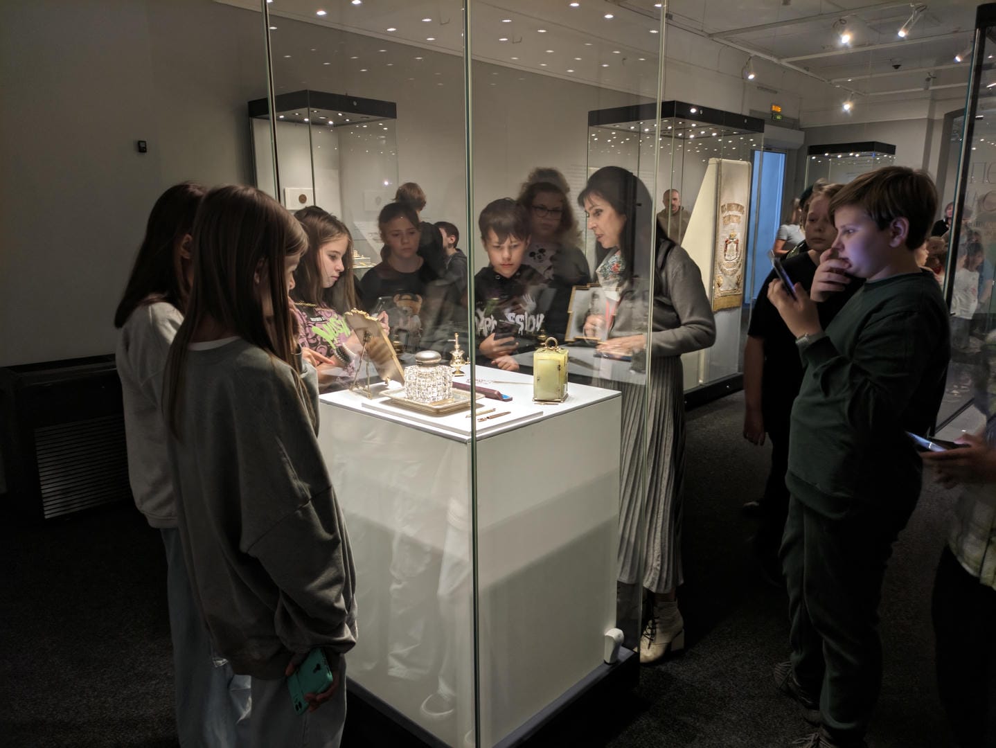 A group of people viewing exhibits inside a glass cabinet.
