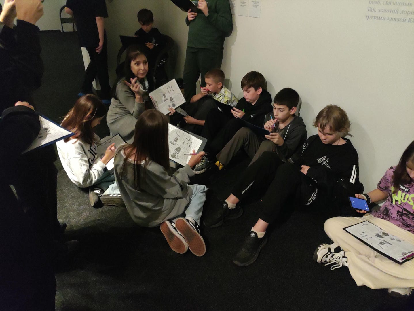 A group of people sitting on the ground, each holding an art book.