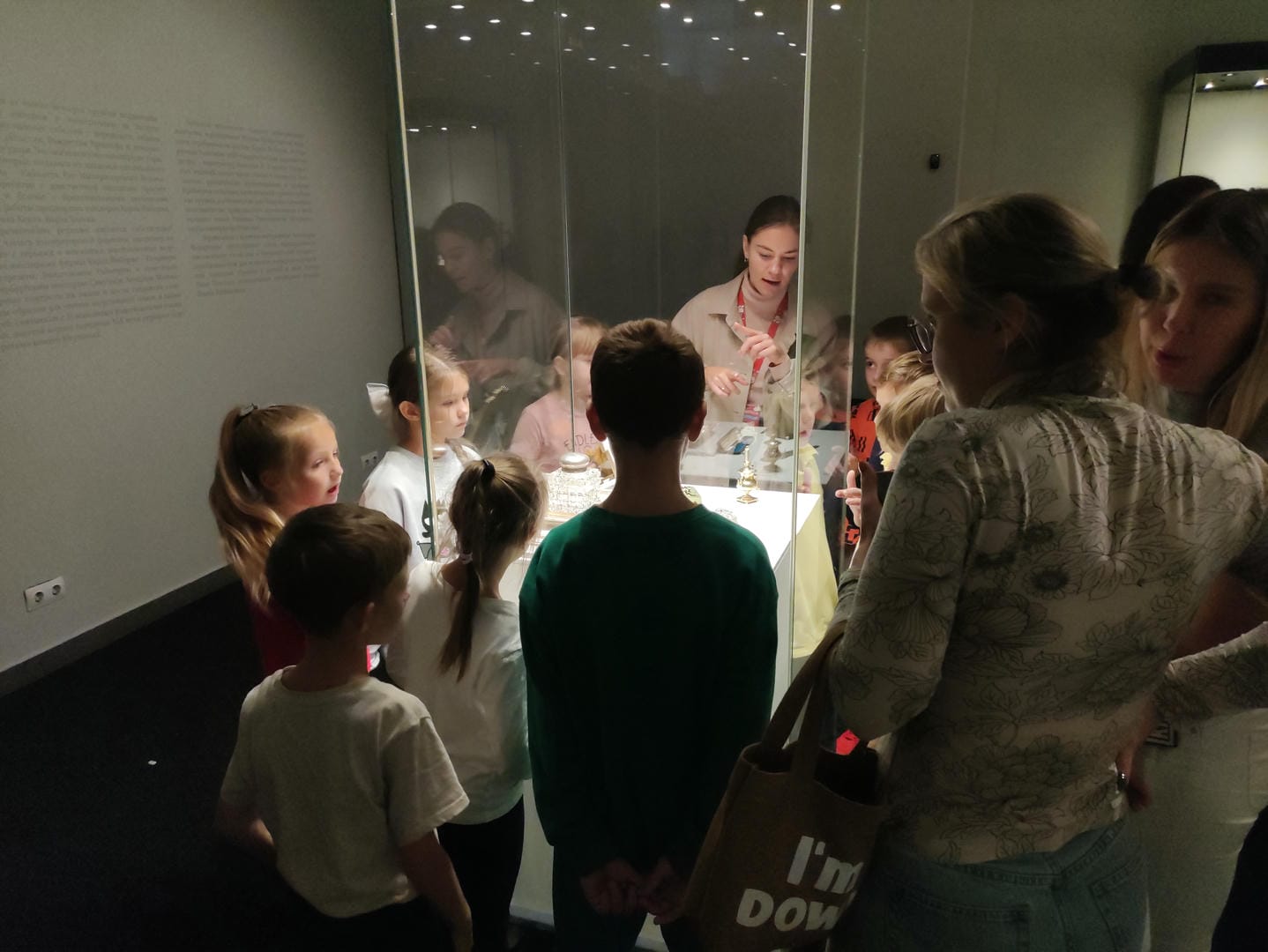 A group of children listening to a guide introducing the exhibits.