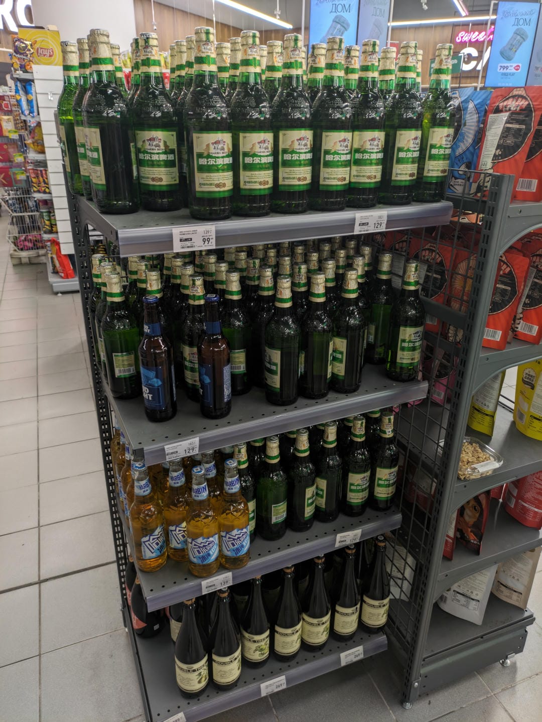 Supermarket shelves stocked with beer bottles of various brands.
