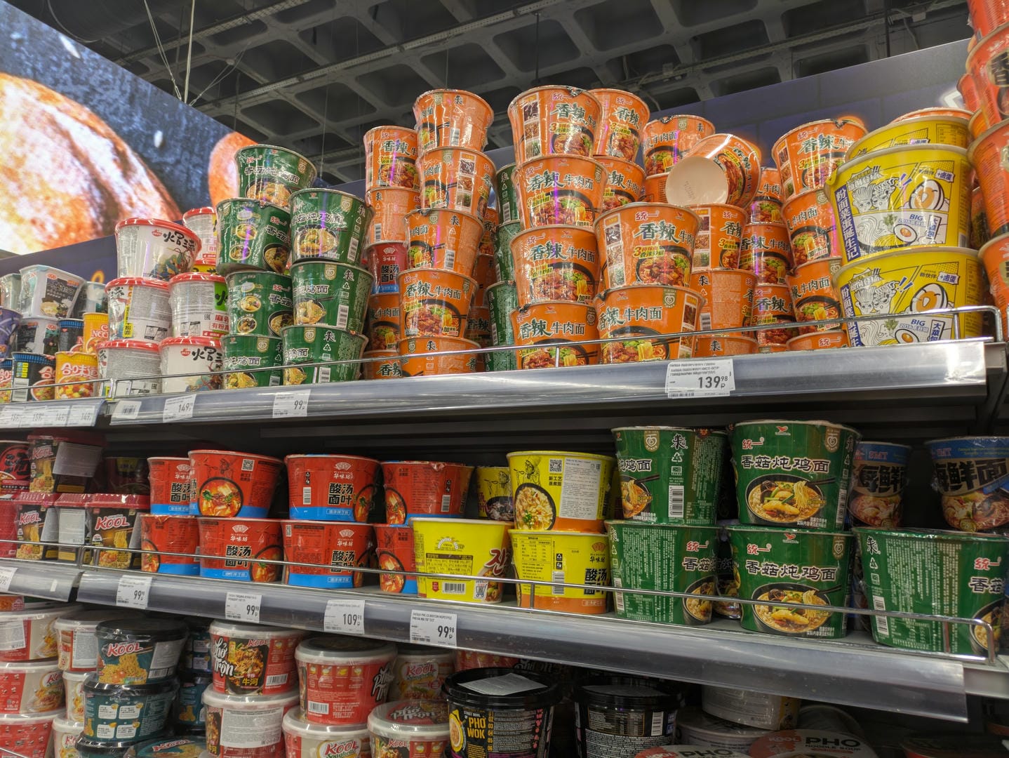 Supermarket shelves piled high with bucket products of instant noodles in various colors.
