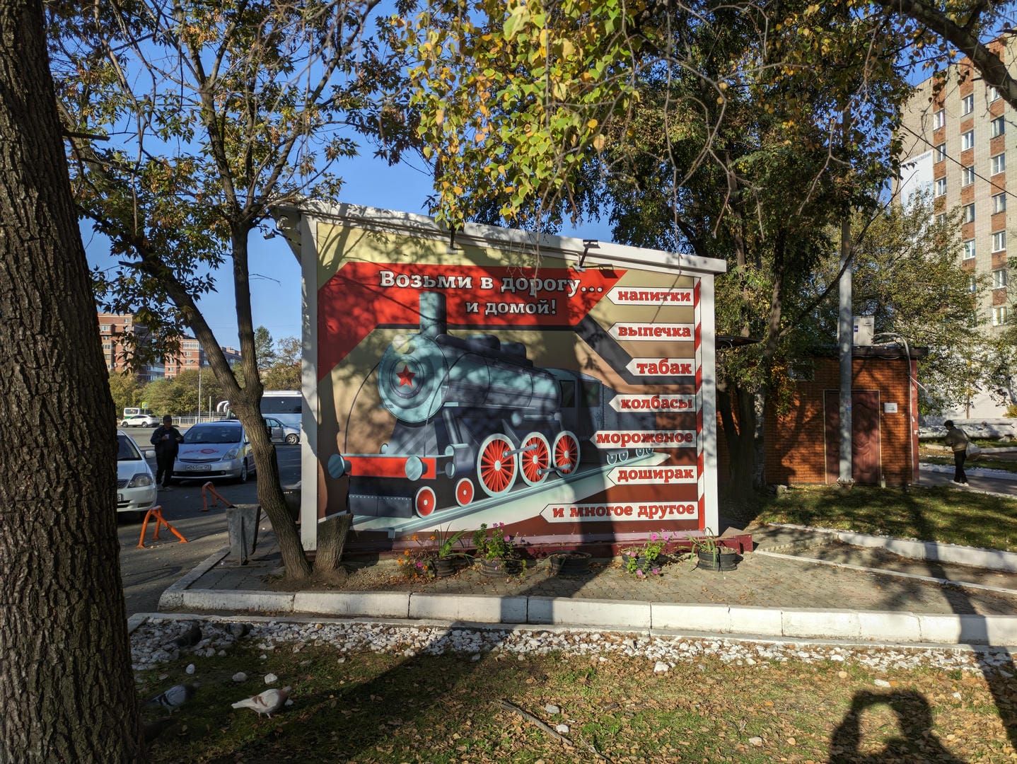 An outdoor billboard displays a train, surrounded by Russian and Chinese signs.