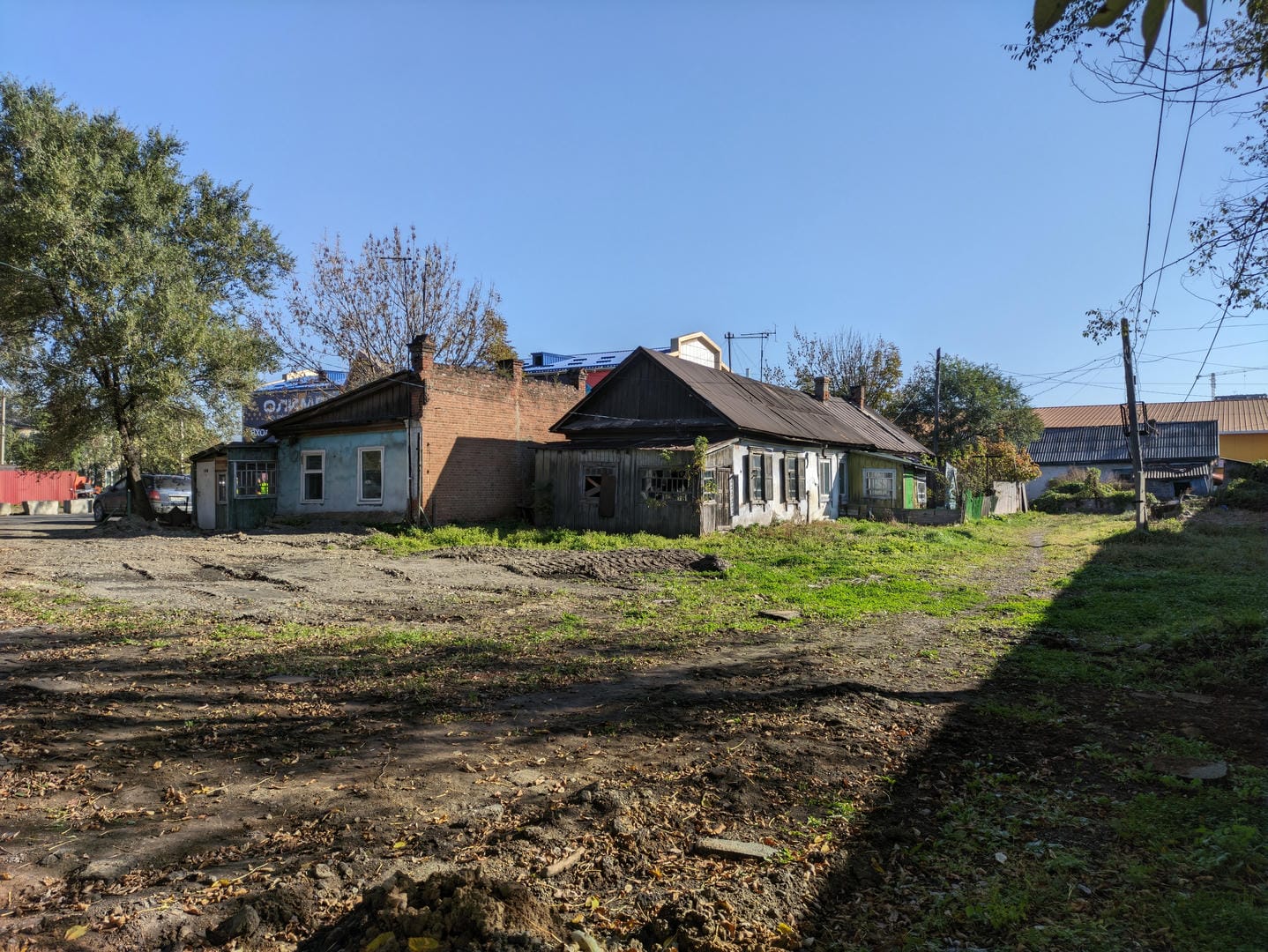 A dilapidated house with a brown roof, surrounded by trees and grass.