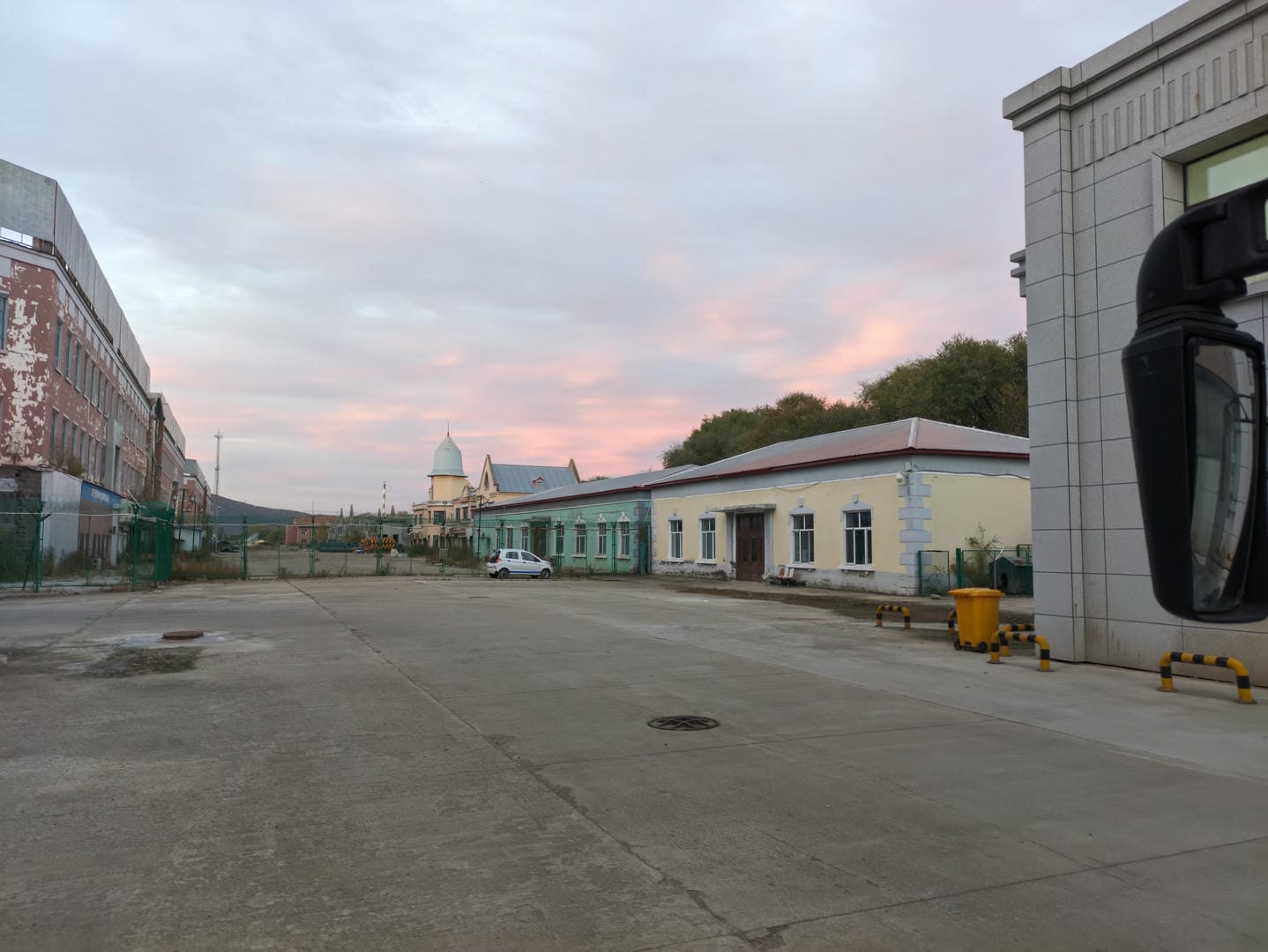 A street lined with buildings, the sky tinted pink.