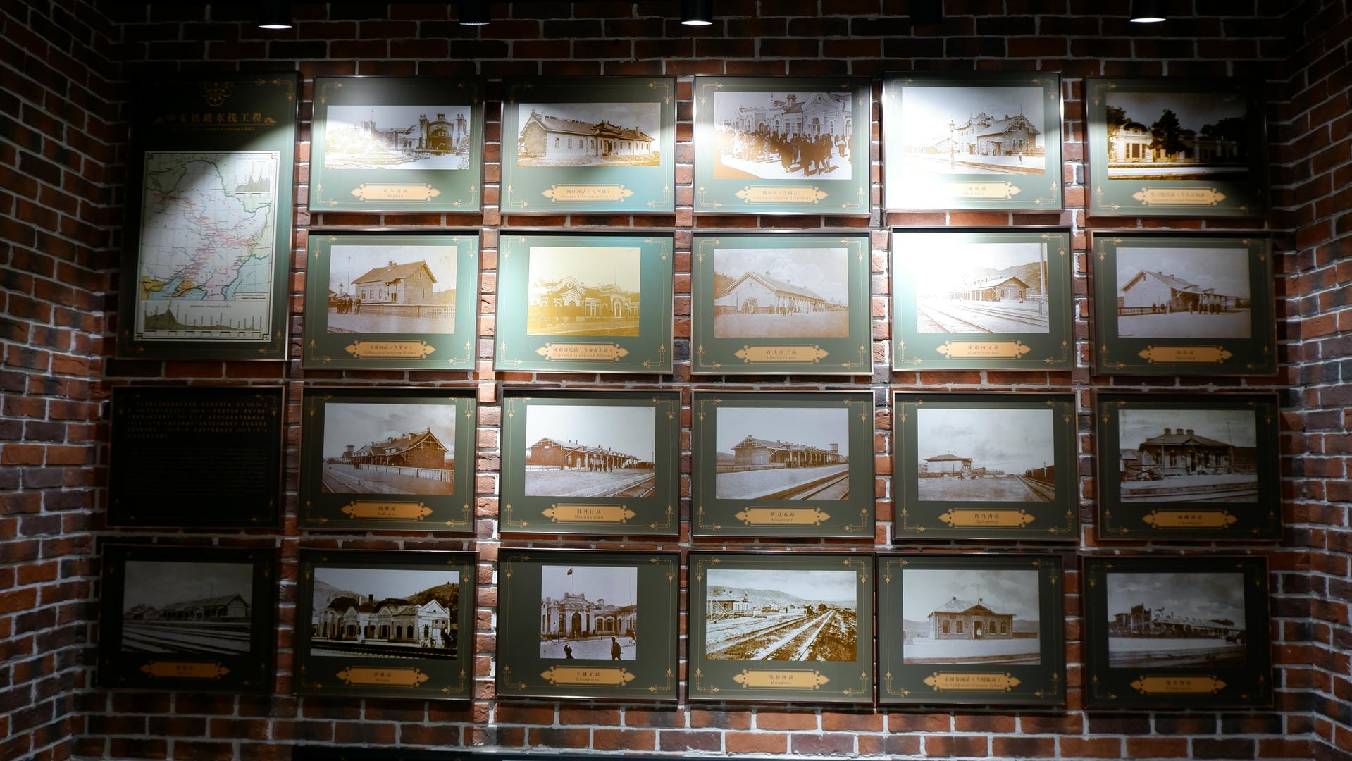 Many framed historical photos hang on a red brick wall, with a larger map on the left side.