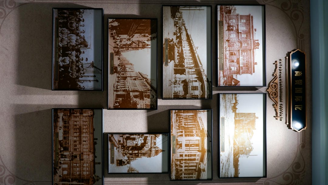 Multiple old photographs are displayed on the wall, with a sign above reading “International Trade.”