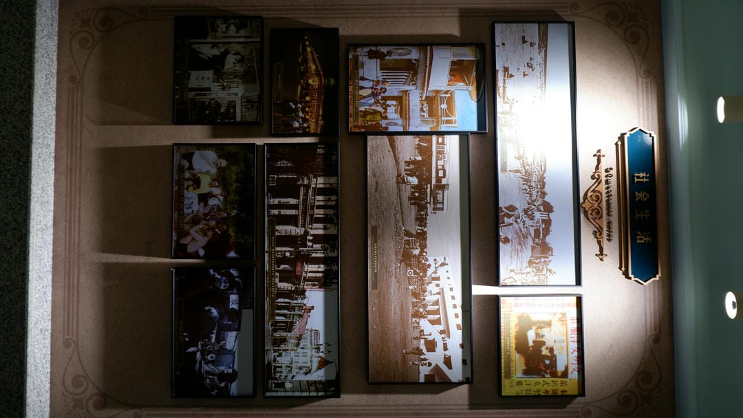 Multiple old photographs are displayed on the wall, with a sign above reading “Social Life.”