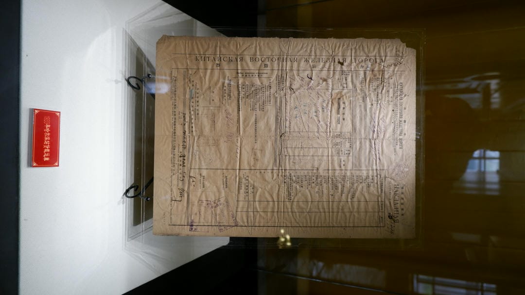 An old document with blurred text is placed inside a glass display case.