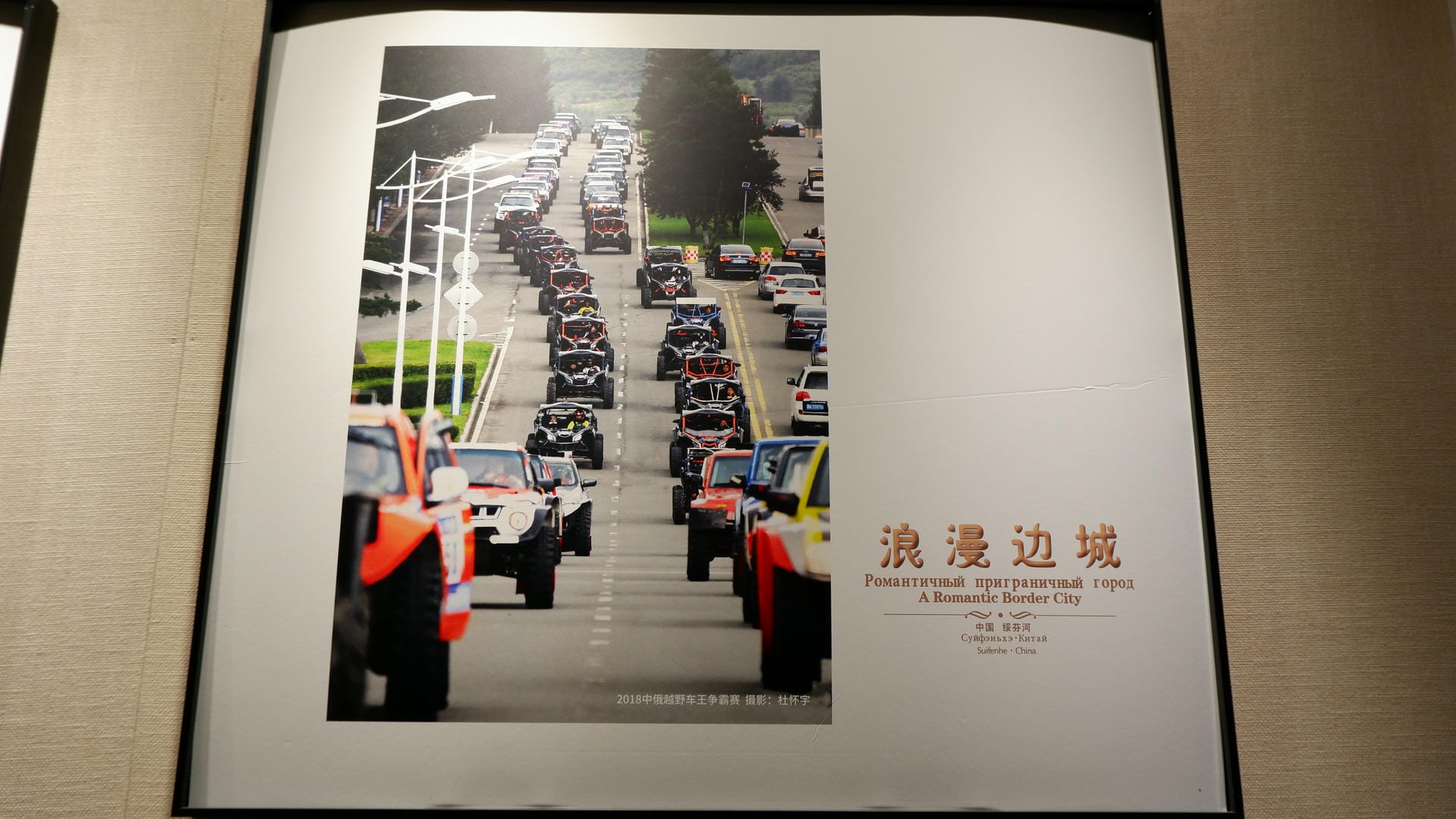A painting displays a row of off-road vehicles neatly lined up on a road.