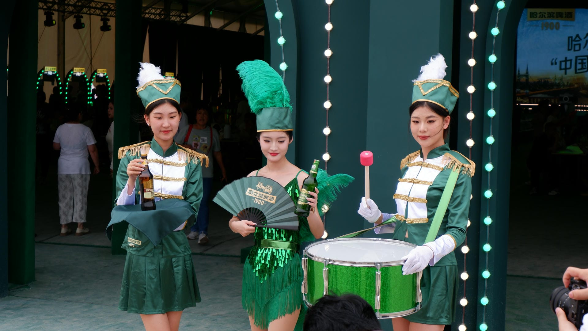 there are three girls in green uniforms holding drums and a fan