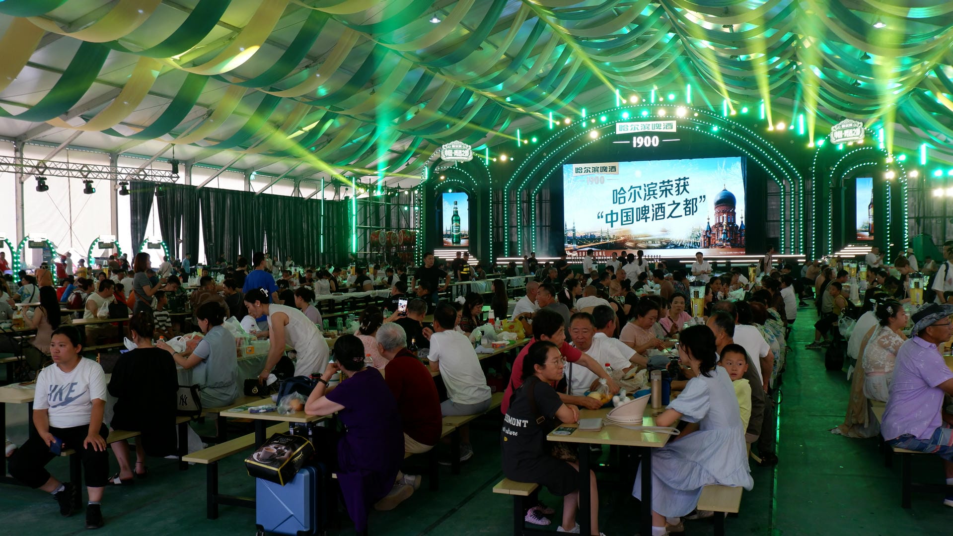 people sitting at tables in a large tent with a screen