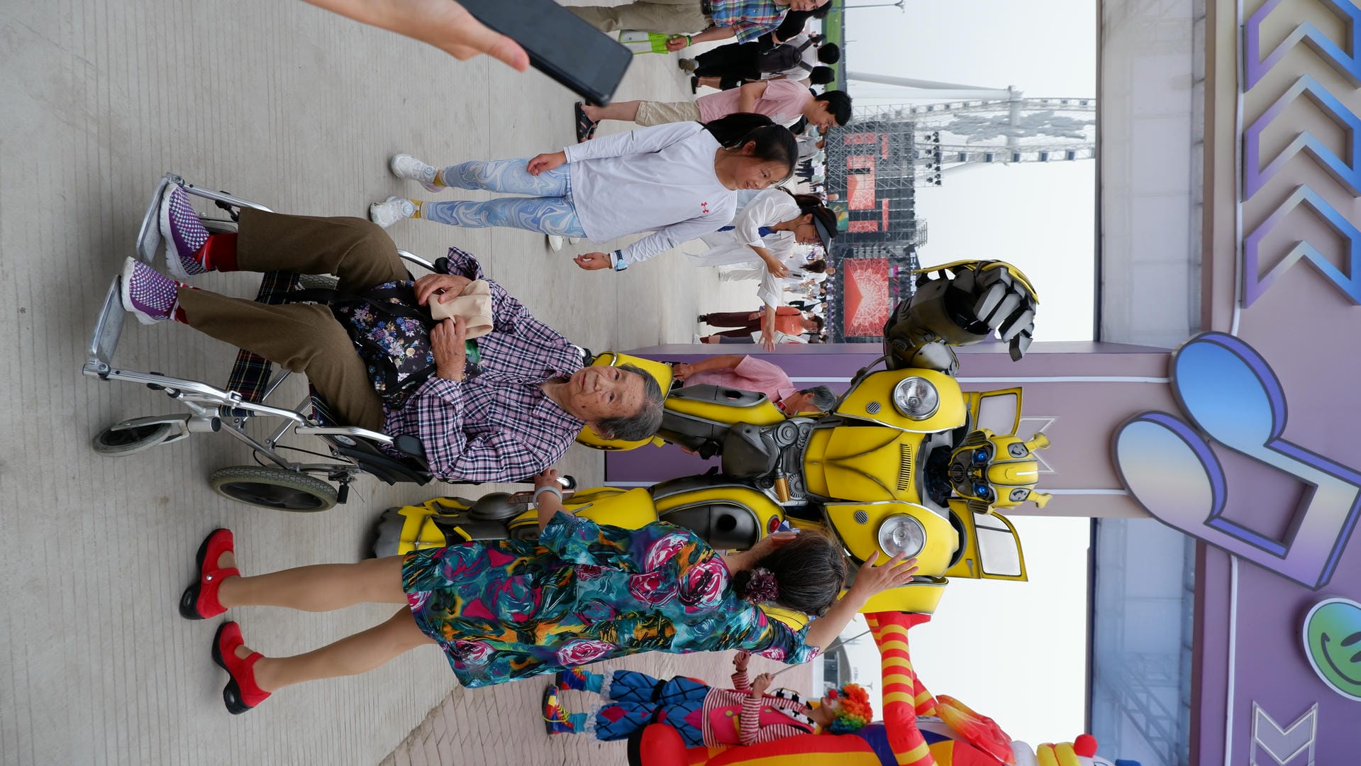 people are standing around a man in a wheelchair and a robot