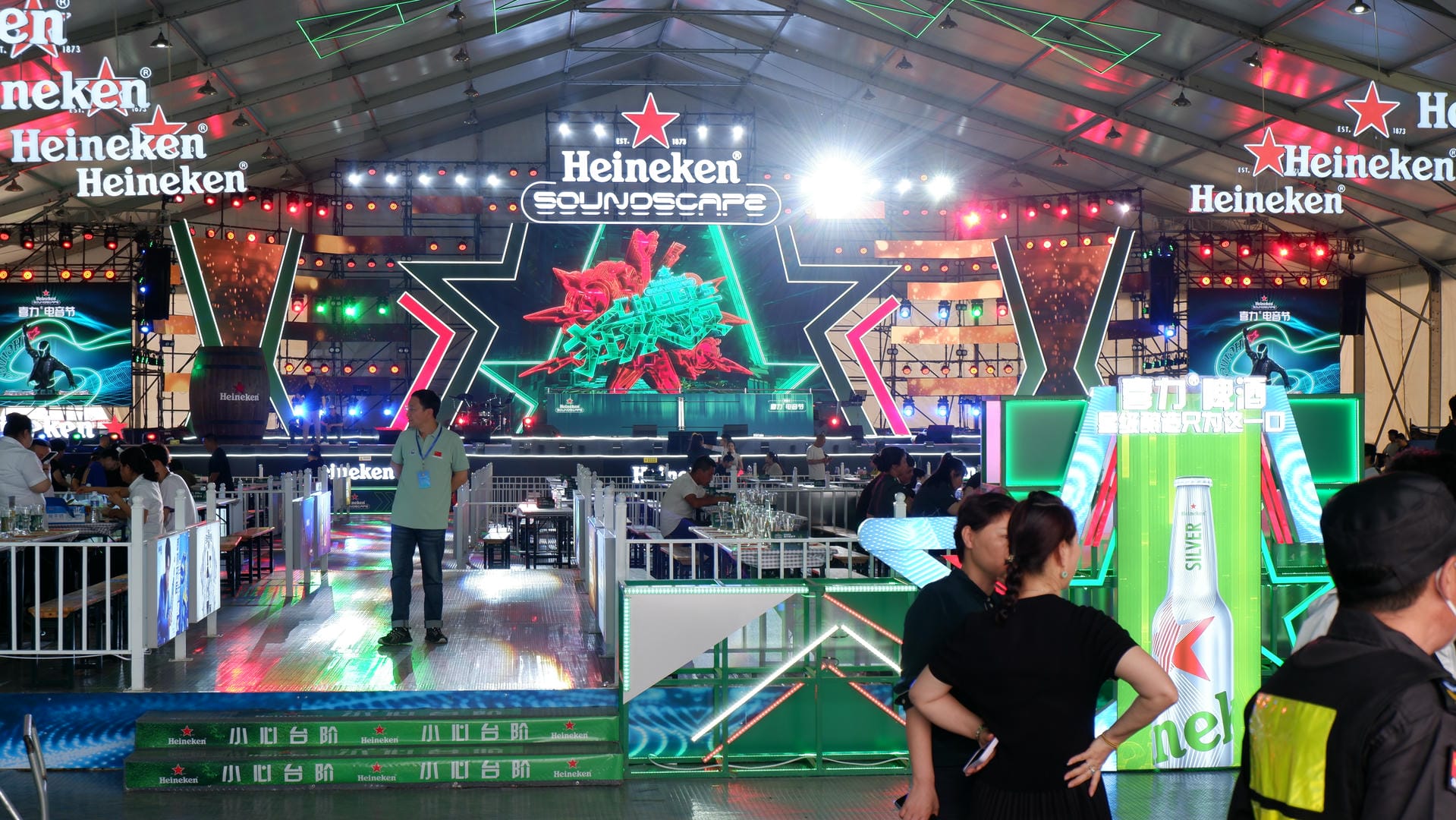 people standing in front of a stage with neon lights and a sign